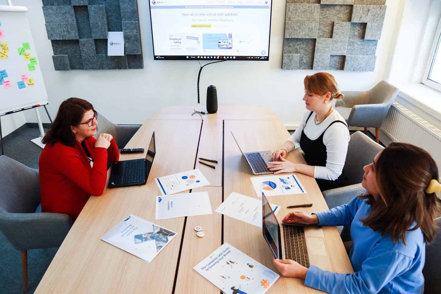 Tre donne collaborano attorno a un tavolo con laptop in un ufficio.