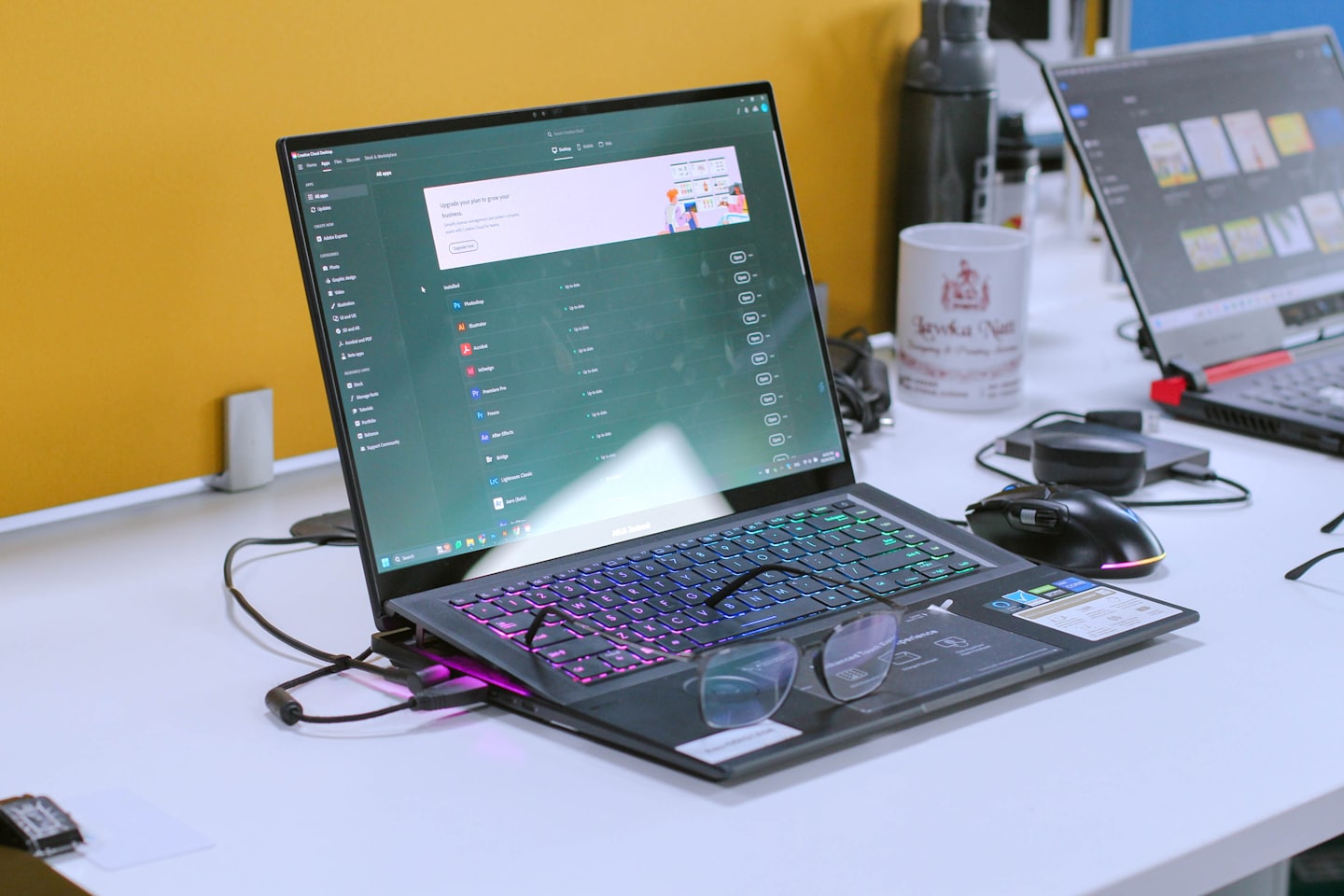 Computer portatile con software aperto e occhiali su una scrivania.