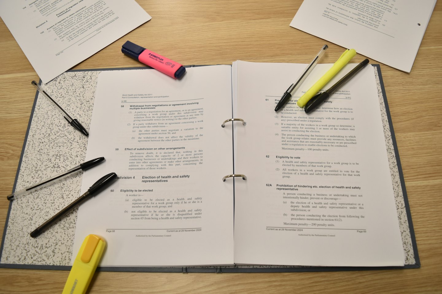 Documenti legali e evidenziatori colorati su una scrivania di legno.